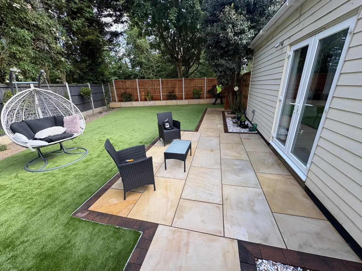 Landscaped garden with natural stone paving, artificial lawn and outdoor furniture